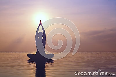 Woman practicing yoga, silhouette on the beach at sunset