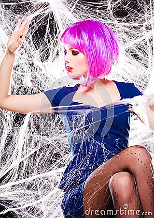 Woman with purple wig and intense make-up trapped in a spider web