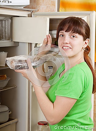 Woman putting raw frozen fish into refrigerato