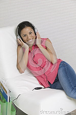 Woman reclining on chair Listening to Music on headphones portrait