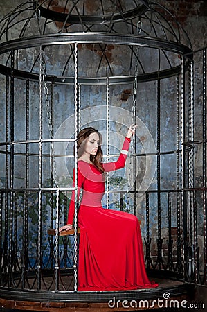 Woman in red dress in cage. Elegance