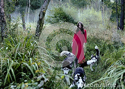 Woman in red dress with tree wolfs in forest