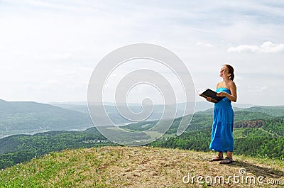 Red haired woman with book on the hilltop