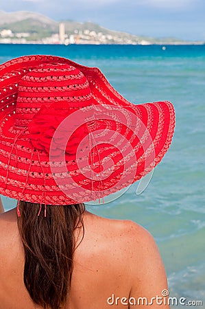 Woman with red hat looking at the sea