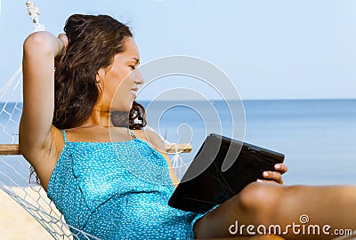 Woman relaxing on hammock and using digital tablet