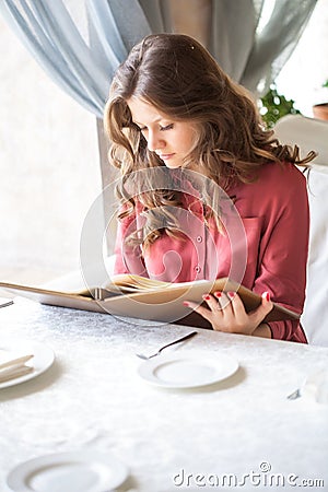 A woman in a restaurant with the menu in hands