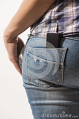 Woman s back in blue jeans with music device