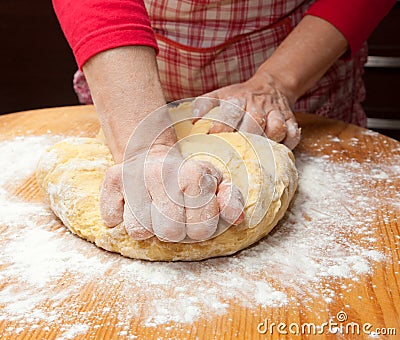 Woman s hands knead dough on wooden table