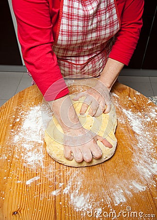 Woman s hands knead dough on wooden table