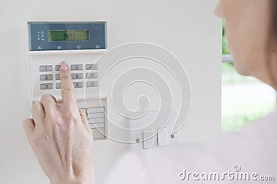 Woman Setting Control Panel On Home Security System