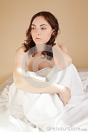 Woman sitting in bed on the white bed-clothes