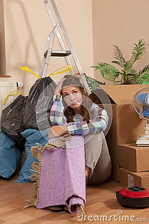 Woman sitting on the floor between waste and moving boxes