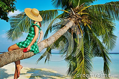 Woman sitting on a palm tree at tropical beach