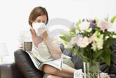 Woman Sitting On Sofa Blowing Nose