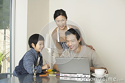 Woman And Son Watching Man Use Laptop