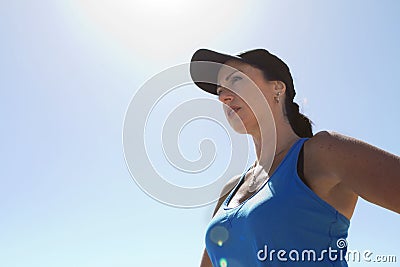 Woman in sports gear and cap with backlighting