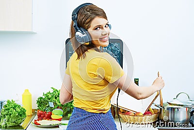 Woman standing back in kitchen, cooking healthy food with fun a