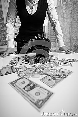 Woman standing behind table with banknotes and piggy bank