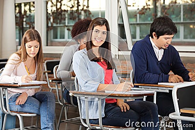 Woman With Students Writing Exam In Classroom