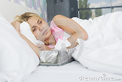 Woman suffering from cold lying with tissue box on bed