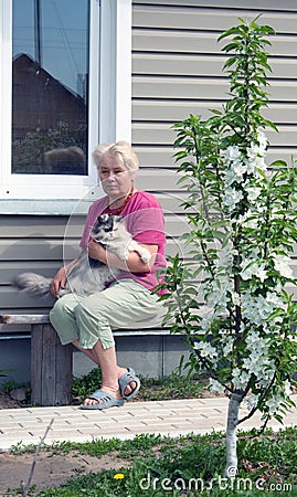 Woman on a summer residence with a cat on hands