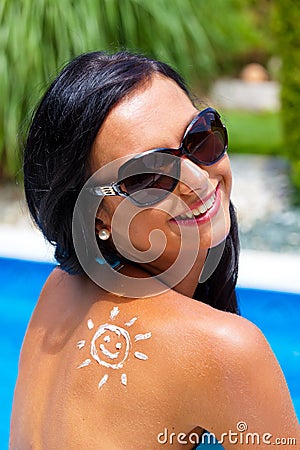 Woman with sun cream by the pool