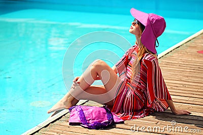 Woman sunbathing in bikini at tropical travel resort. Beautiful young woman lying on sun lounger near pool.