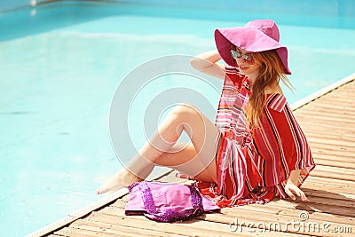 Woman sunbathing in bikini at tropical travel resort. Beautiful young woman lying on sun lounger near pool.