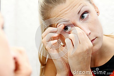 Woman take out contact lens of her eye