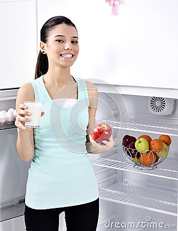 Woman take red apple and milk from fridge