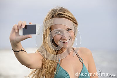 Woman taking photo with cellphone on the beach