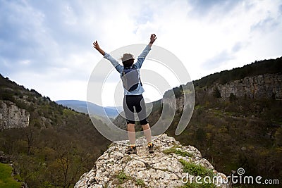 Woman on top of the mountain reaches for the sun