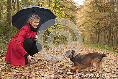 Woman with umbrella playing with her dog