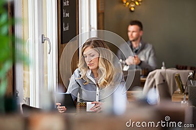 Woman Using Digital Tablet With Man In Background