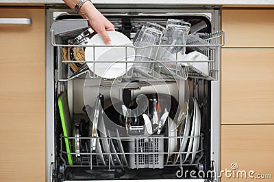 Woman is using a dishwasher in a modern kitchen