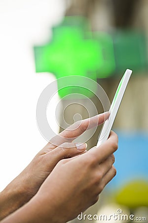 Woman using her cell phone in front neon sign pharmacy