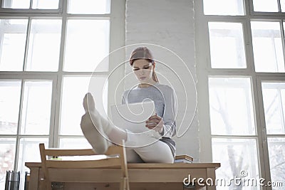 Woman Using Laptop On Desk In Loft Apartment