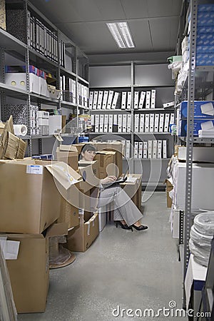 Woman Using Laptop In Office Storage Room