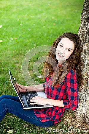 Woman using a laptop under a tree