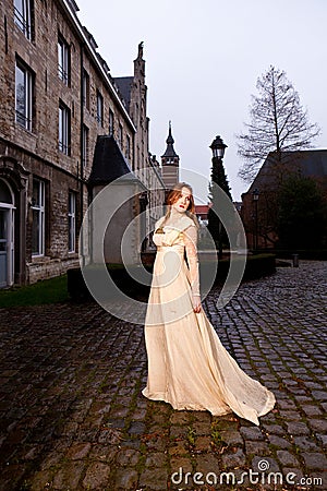 Woman in Victorian dress in a old city square in the evening walking