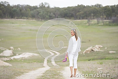Woman walking bare feet outdoor holding high heels
