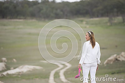 Woman walking in park holding high heel shoes