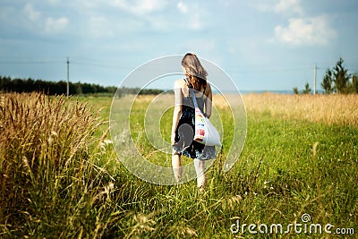 Woman walking through sunshine green and yellow corn field