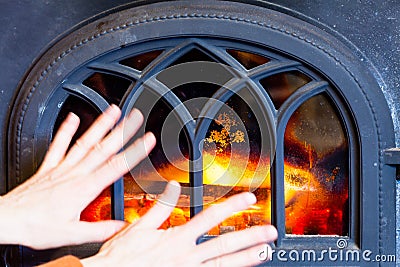 Woman warming hands at fire fireplace interior.