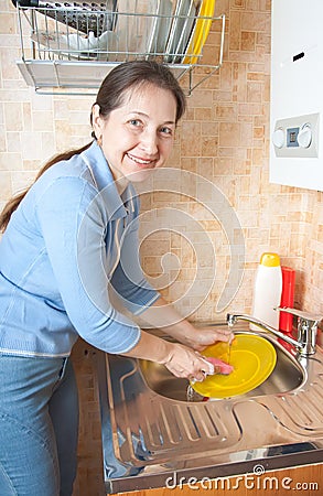 Woman washes ware on kitchen
