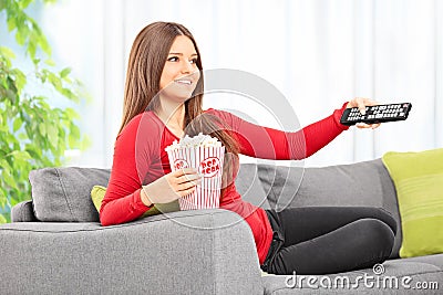 Woman watching tv seated on sofa at home