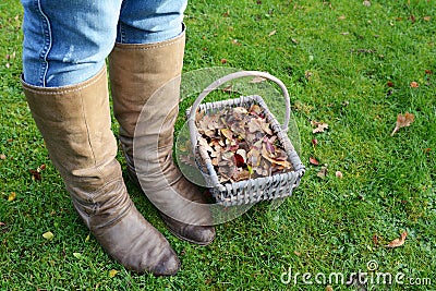 Woman wearing boots standing with a basket of fall leaves