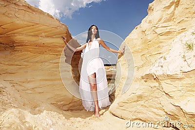 Woman in white dress dancing on the desert