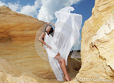 Woman in white dress dancing on the desert