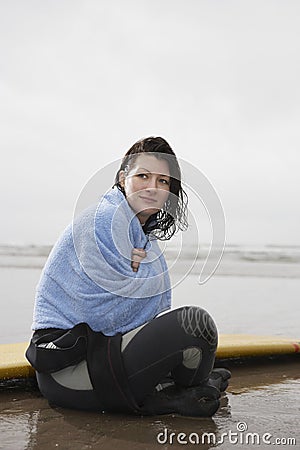 Woman Wrapped In Towel Looking Away While Sitting On Beach
